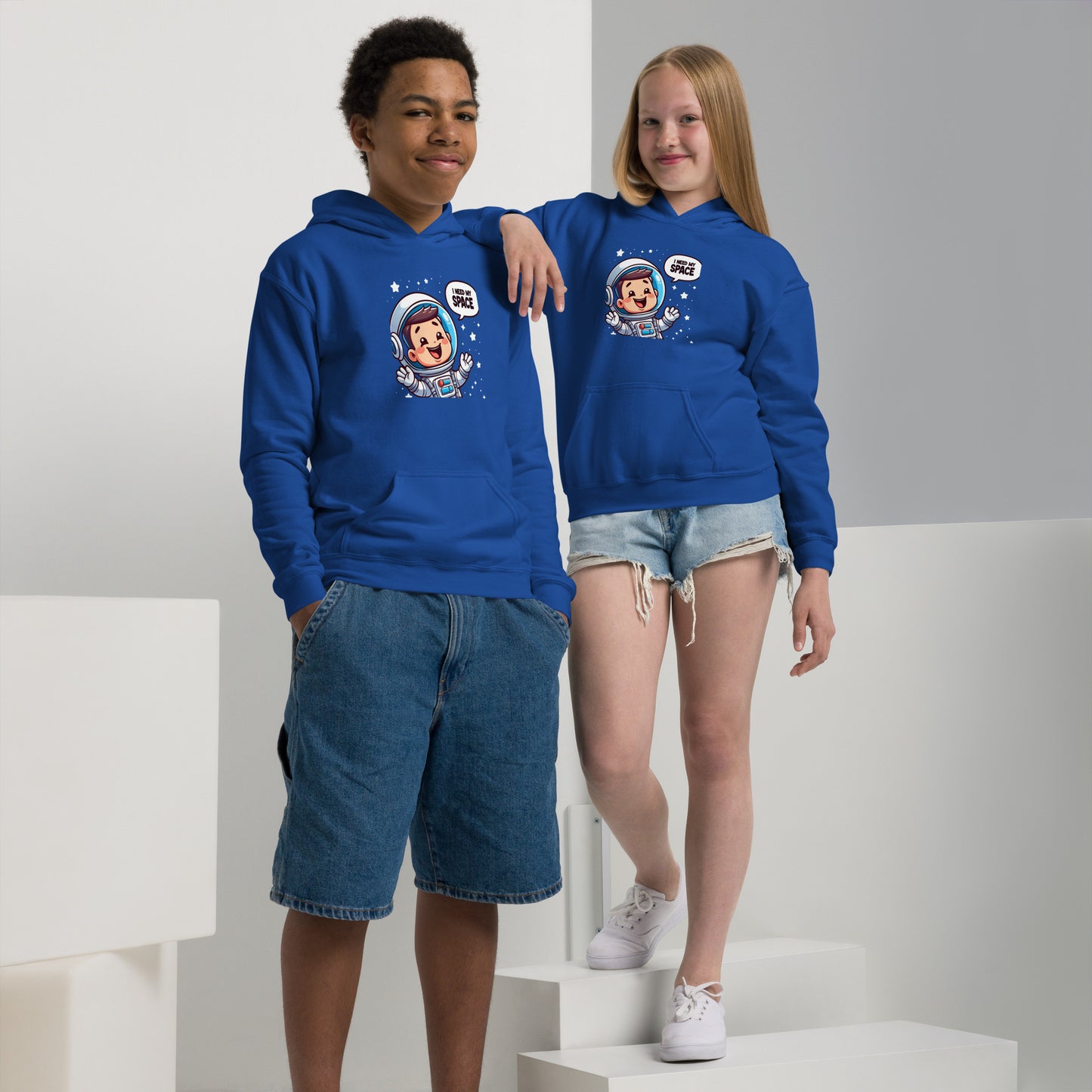 Two kids wearing a heavy blend space hoodie in blue featuring an astronaut design for a fun outer space theme