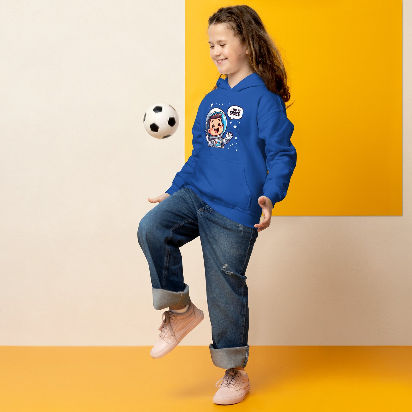 Child wearing a blue heavy blend space hoodie with a fun graphic design and relaxed fit while juggling a soccer ball