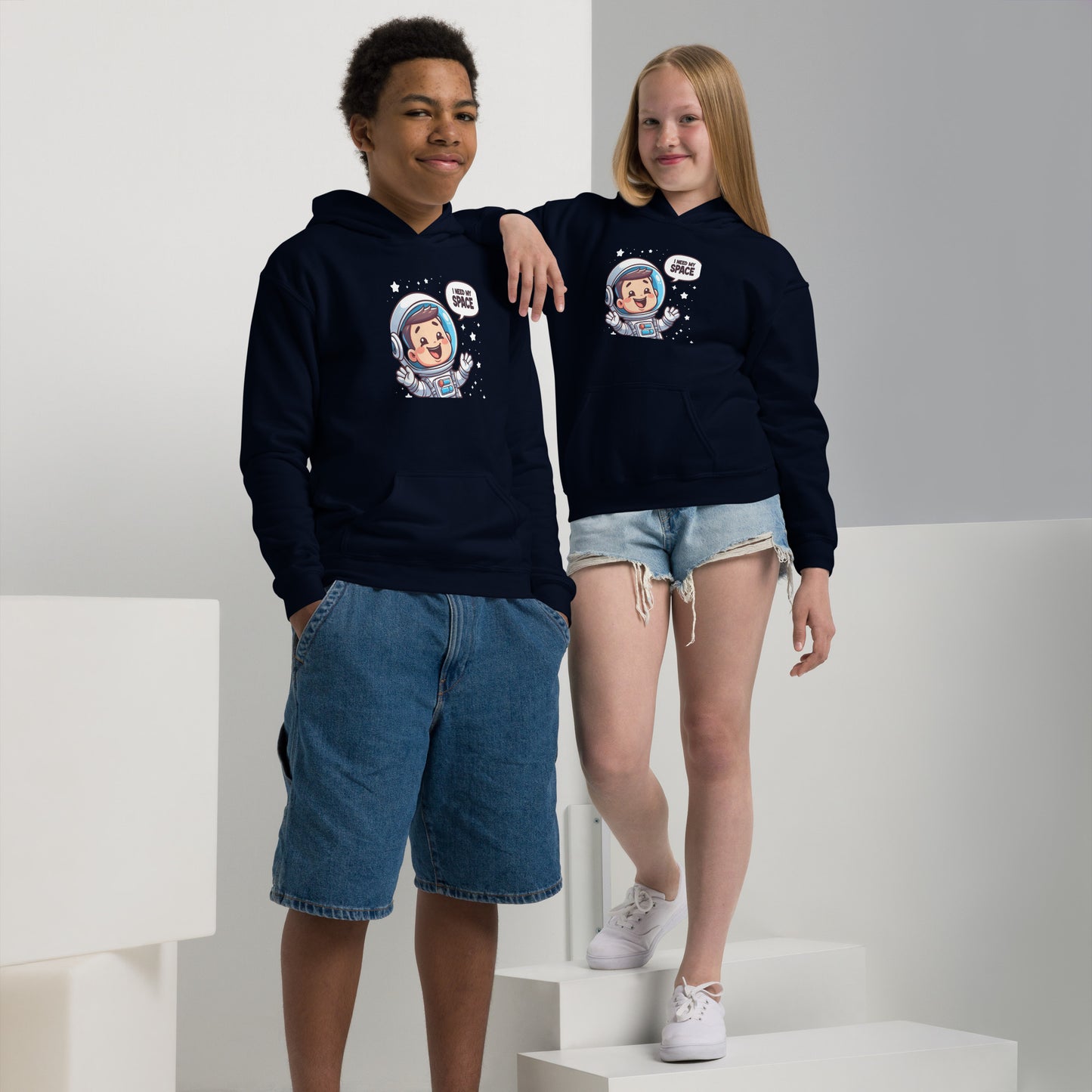 Heavy blend space hoodie featuring colorful astronaut graphic worn by a boy and girl on a minimalist background