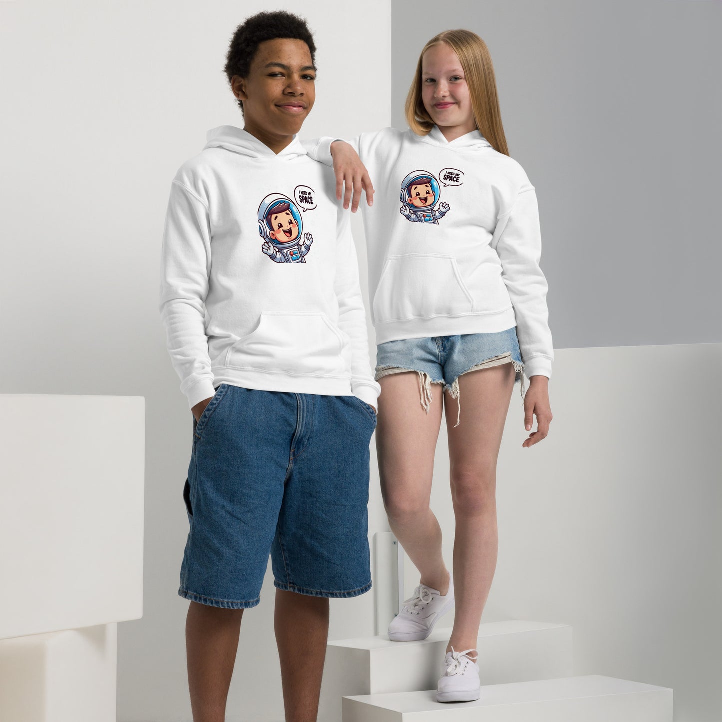 Two kids wearing a white heavy blend space hoodie featuring a cute astronaut design